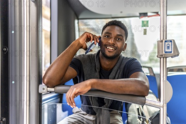 Young african confident businessman with casual clothes talking to the mobile while traveling by bus