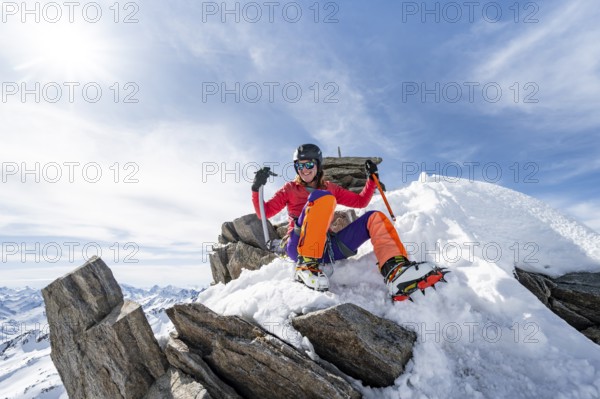 Happy mountaineer with ice axes and crampons on the summit of Piz Grialetsch in winter, Graubünden Haute Route, Albula Alps, Rhaetian Alps, Graubünden, Switzerland, Europe