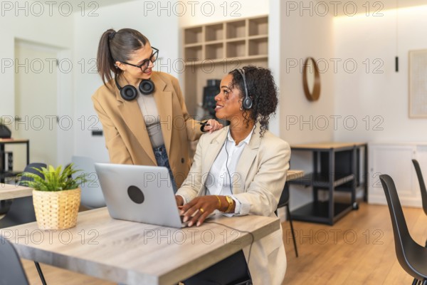 Two female colleagues collaborating on a project, demonstrating teamwork and support in a modern workspace