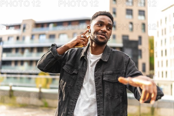 African cool man listening to music with earbuds and dancing in the city street