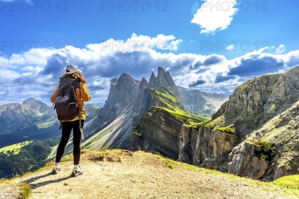 Female tourist with backpack admiring the odle mountain range in the italian dolomites on a sunny summer day