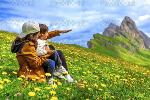 Mother and child admiring the landscape in the seceda mountains in the dolomites, italy, during a summer day