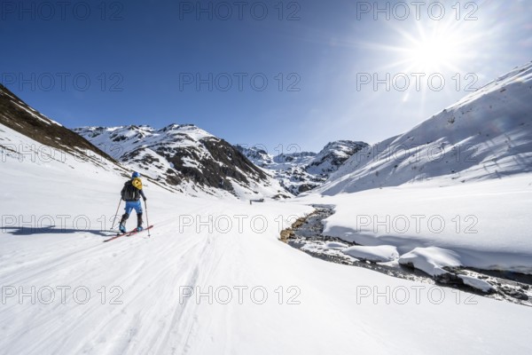 Ski tourer in the snow by a mountain stream in the Funtauna Valley, Sonnenstern, Graubünden Haute Route, Albula Alps, Rhaetian Alps, Graubünden, Switzerland, Europe