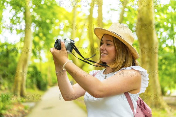 Close up side view of a caucasian young cheerful woman hiking in the forest with camera