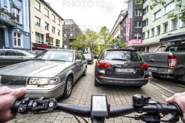 Cycling in the city, inner-city street, cycle lane, bicycles have priority, two-lane traffic with parked cars on both sides, cyclists' perspective, Essen, North Rhine-Westphalia, Germany, Europe