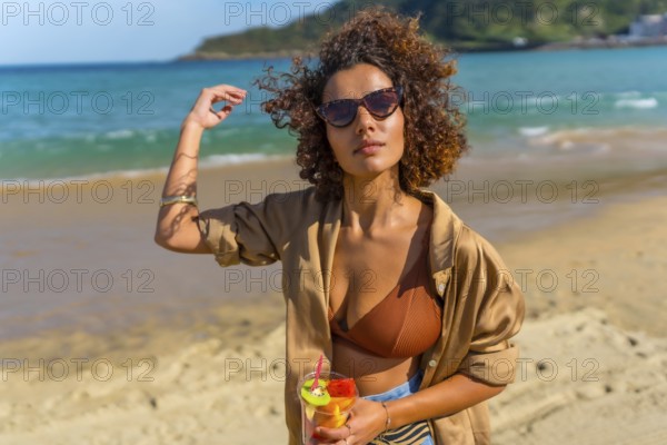 Sensual arab woman walking along topical beach with a glass of fruit