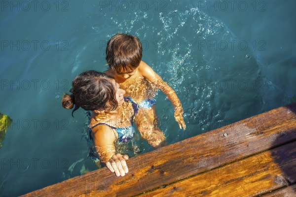 Mother and son having fun swimming in the turquoise water of lake bled, a popular tourist destination in the julian alps