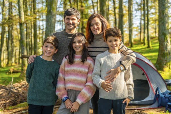 Portrait of a happy caucasian family with three children enjoying nature and camping together standing smiling at camera