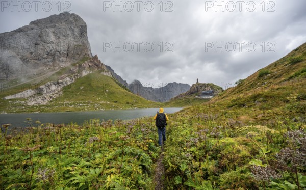 Mountaineer on hiking trail at Wolayersee, Alpine Club hut Wolayerseehütte, rocky cloudy mountains, Carnic Alps, Carnic High Trail, Carinthia, Austria, Europe