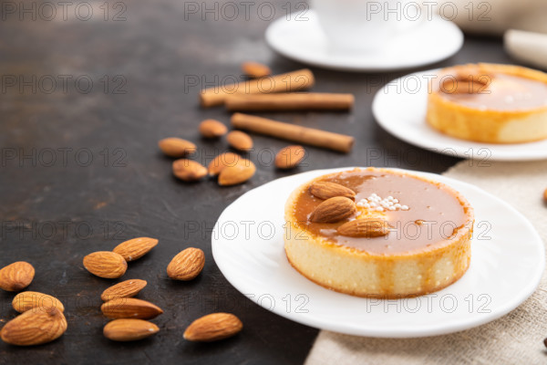 Sweet tartlets with almonds and caramel cream with cup of coffee on a black concrete background and linen textile. Side view, close up, selective focus
