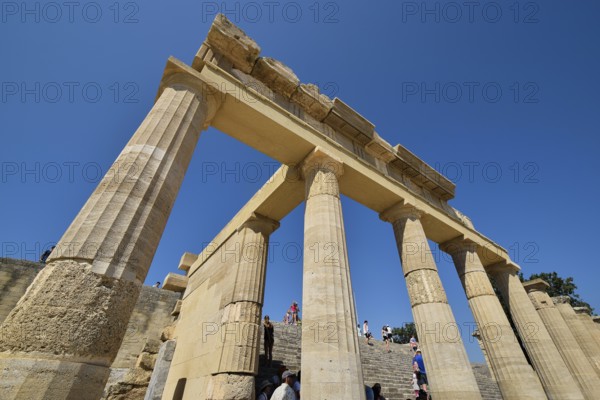 Super wide angle shot, Ancient ruins with columns under a clear blue sky on a sunny day full of tourists, morning light, Propylaea, Lindos, Rhodes, Dodecanese, Greek Islands, Greece, Europe