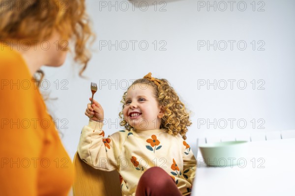 Playful girl eating and joking with her mother at home