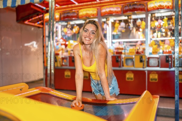 Blonde woman smiling at camera playing hockey at a fair at night