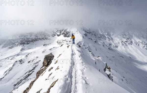Mountaineer climbing up the narrow ridge of Piz Laviner, view of wintry mountain landscape, Grisons Haute Route, Albula Alps, Rhaetian Alps, Grisons, Eastern Switzerland, Switzerland, Europe
