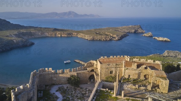 Drone shot, Acropolis of Lindos, Late afternoon light, Rock fortified historical site above a calm bay in the morning light, Archaeological site, Lindos, Rhodes, Dodecanese, Greek Islands, Greece, Europe