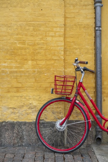Red bicycle in front of yellow wall, heritage-protected building Søkvæsthuset, former naval hospice, Christianshavn Canal, Christianshavn, Copenhagen, Denmark, Europe