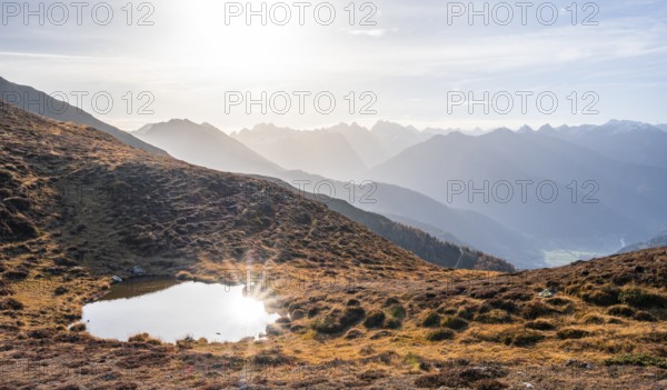 Small mountain lake on the Krahberg, sun star in the morning, mountain panorama in autumn, Venet crossing, Ötztal Alps, Tyrol, Austria, Europe