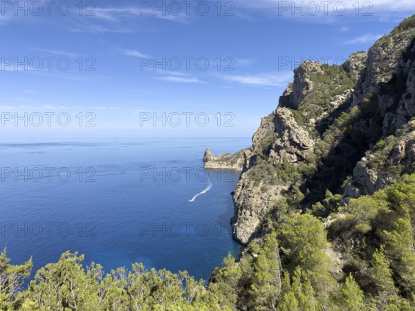 Rugged cliffs overlooking the deep blue sea, crossed by a boat on the water, Cala d'en Sardina, Ibiza, Balearic Islands, Spain, Europe
