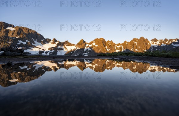 Rocky mountain peaks reflected in a small pond, mountain landscape with alpenglow at sunrise, at the Trollfjord Hytta, at the Trollfjord, Lofoten and Vesterålen, Nordland, Norway, Europe