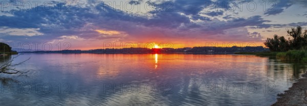 Dramatic sunset over a calm lake with reflecting water, Simssee