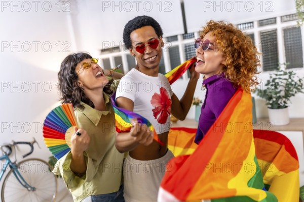 Lesbian couple and transgender friend laughing, singing and dancing, celebrating pride at home