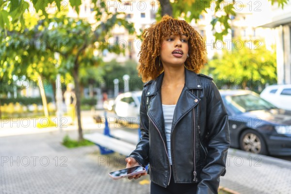 Distracted beauty latin woman listening to music with earbuds and smartphone outdoors in the street