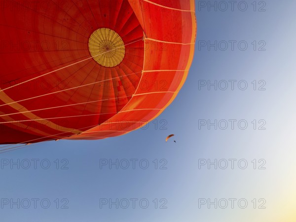 Hot air balloon ride, Paraglider with motor passes the hot air balloon. Background blue sky. Alice Springs, Northern Territory, Australia, Oceania