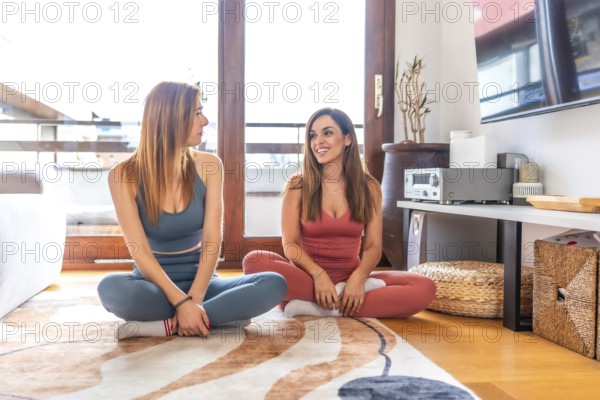 Two friends engaging in an online yoga class, meditating in a cozy living room. They enjoy a peaceful and relaxing environment