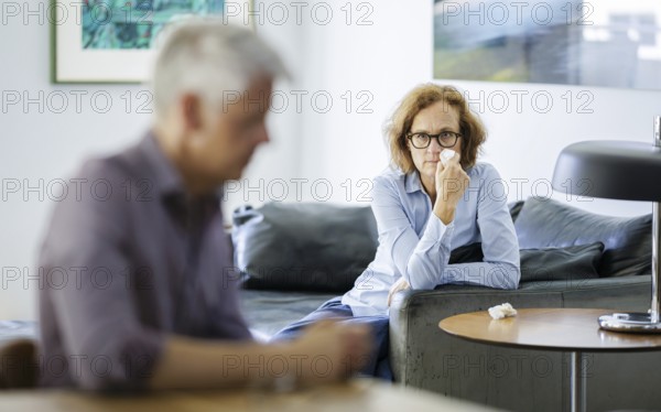 Symbolic photo on the subject of problems in a partnership. An older woman and an older man sitting at home. Berlin, 13.08.2024