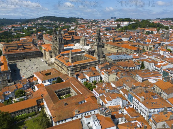 Aerial view of a historic city with a prominent cathedral and orange-coloured tiled roofs