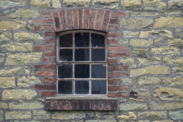 Single window embedded in a masonry stone wall with brick frame in an old farmhouse, North Rhine-Westphalia, Germany, Europe