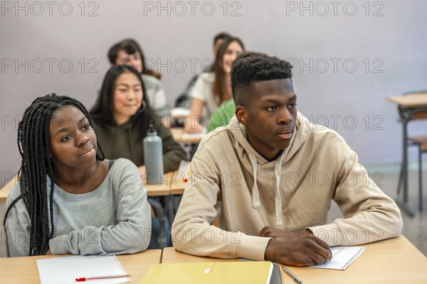 Multi ethnic university students listening attentively to a lecture in a classroom setting, focused on learning and academic achievement