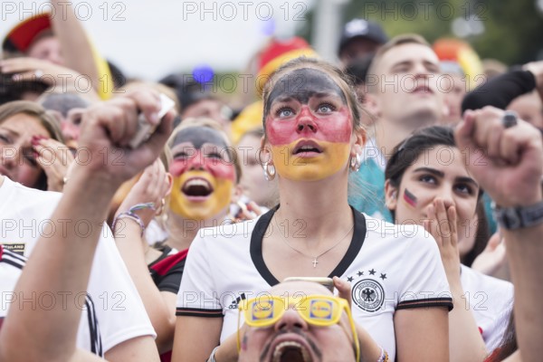 A woman wearing make-up in the German national colours watches the football match in the fan zone at the Brandenburg Tor during the quarter-final match between Germany and Spain at the European Football Championship, Berlin, 05.07.2024