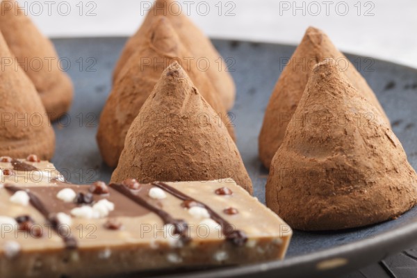 Chocolate truffle on blue ceramic plate on gray concrete background. close up, side view