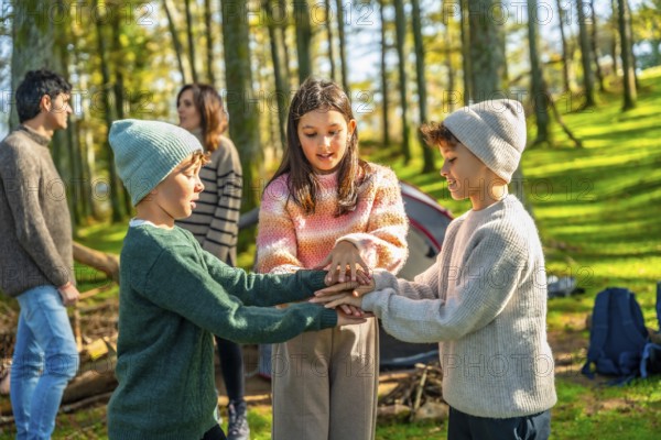 Three caucasian young brothers and sister playing enjoying camping in the forest with their parents