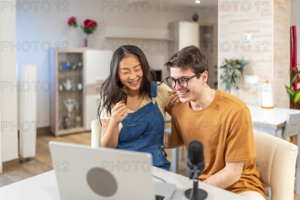 Asian woman and caucasian man smiling while engaging in a fun activity at home, showcasing a joyful and relaxed atmosphere