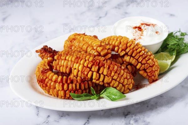 Corn ribs, with cream sauce, spices and lime, appetizer, on a white plate, homemade, no people