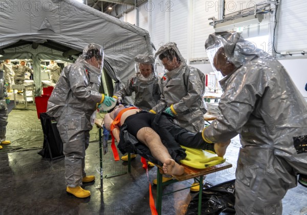 Decontamination of injured persons after an assumed accident involving hazardous substances, fire brigade and aid organisations practise setting up and operating a decontamination station, injured persons are sighted and then washed in a special shower tent to remove possible hazardous substances and chemicals in order to avoid further injuries, the emergency services wear special, ventilated protective suits, large-scale exercise by the Essen fire brigade