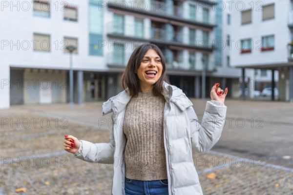 Happy beauty woman with jacket and warm clothes dancing in the city