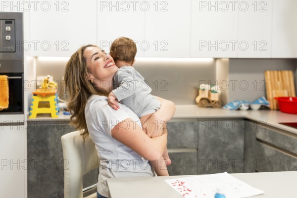 Mom lovingly embraces her baby in a modern kitchen, creating a heartwarming moment of family connection