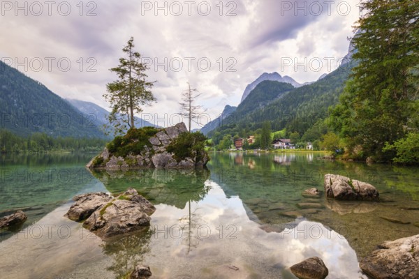 Hintersee with rocks and trees in the foreground, surrounded by mountains after sunset with dramatic cloudy sky, Ramsau, Berchtesgaden National Park, Berchtesgadener Land, Upper Bavaria, Bavaria, Germany, Europe