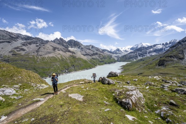 Two mountaineers on a hiking trail at a blue mountain lake, reservoir Lac des Dix, behind mountain peak Mont Blanc de Cheilon, Hérménence, Valais Alps, Valais, Switzerland, Europe