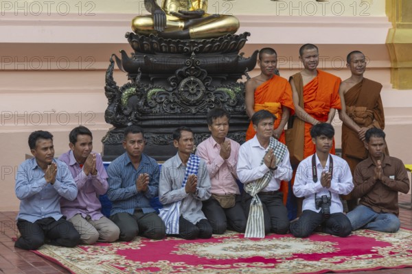 Monks and Laotians in front of a Buddha statue, Bhumispara-mudra, Buddha Gautama at the moment of enlightenment, Wat Ong Teu, Vientiane, Laos, Asia