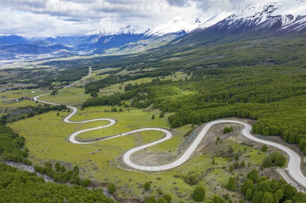 Road Carretera Austral winding down into the valley of Villa Cerro Castillo, snowcapped mountains in early spring, Patagonia, Chile, South America