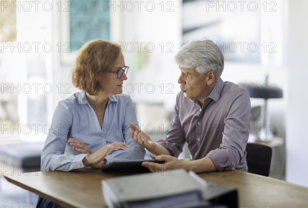 Symbolic photo. A woman and a man sit together at a table with a tablet and talk. Berlin, 13.08.2024