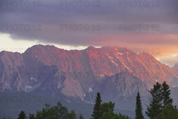 Mountain peak in bright red at sunset with dramatic clouds in the sky, Wallgau, Bavaria, Germany, Europe