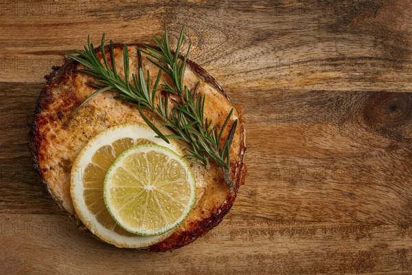 Salmon steak, fried, on a cutting board, top view, rosemary, lemon and lime, homemade, one serving, no people
