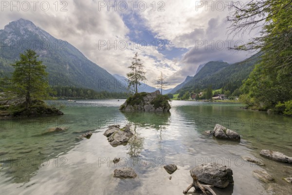 Hintersee with rocks and trees in the foreground, surrounded by mountains after sunset with dramatic cloudy sky, Ramsau, Berchtesgaden National Park, Berchtesgadener Land, Upper Bavaria, Bavaria, Germany, Europe
