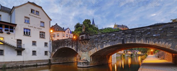 Town view of Vianden with the old stone bridge over the river Our and the castle in the evening, Grand Duchy of Luxembourg