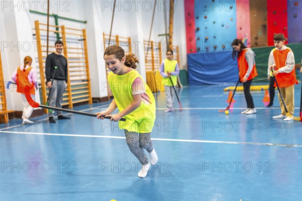 Elementary school children playing floorball in gym class, learning teamwork and sportsmanship through physical activity